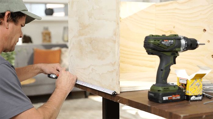 un hombre marca el lugar de las fijaciones de la parte trasera del mueble.