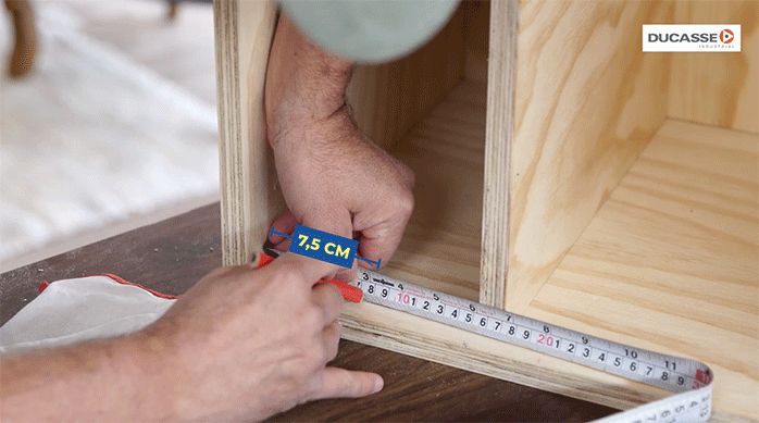 un hombre marca el lugar del riel dentro de la estructura del mueble.