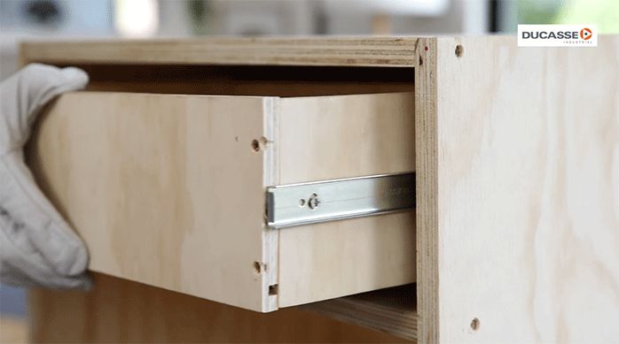 un hombre inserta el cajón en el mueble haciendo calzar los rieles y comprobando su buen funcionamiento.