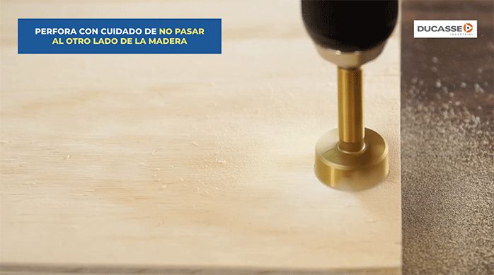 una persona perfora la puerta del mueble con una broca especial para bisagras de 35 mm.