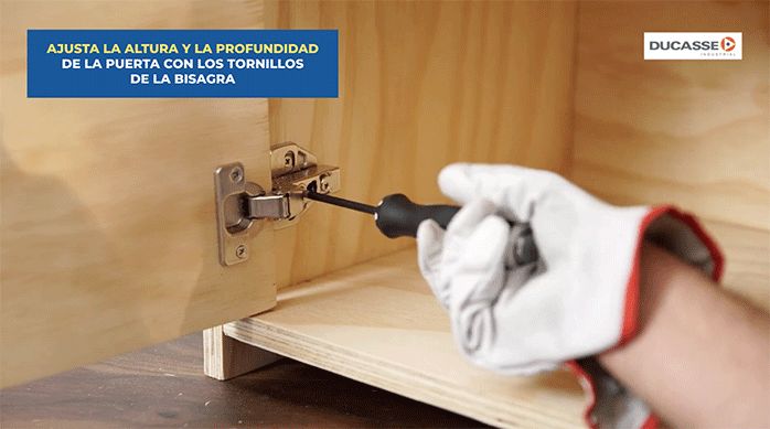 un hombre regula la bisagra en el mueble con un desatornillador manual.