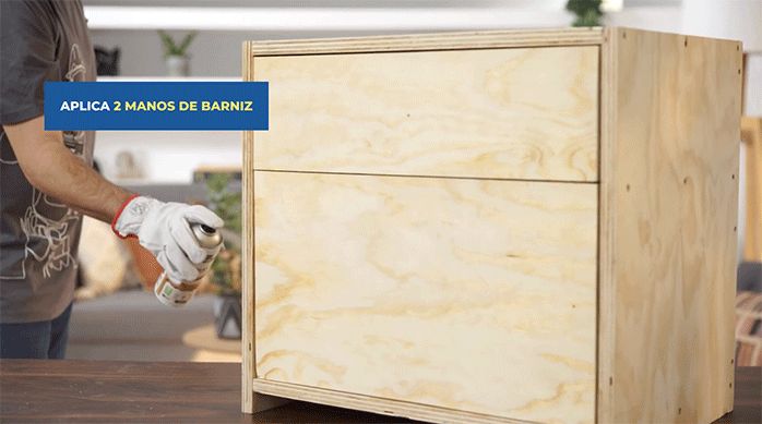 un hombre aplica dos manos de barniz en el mueble.
