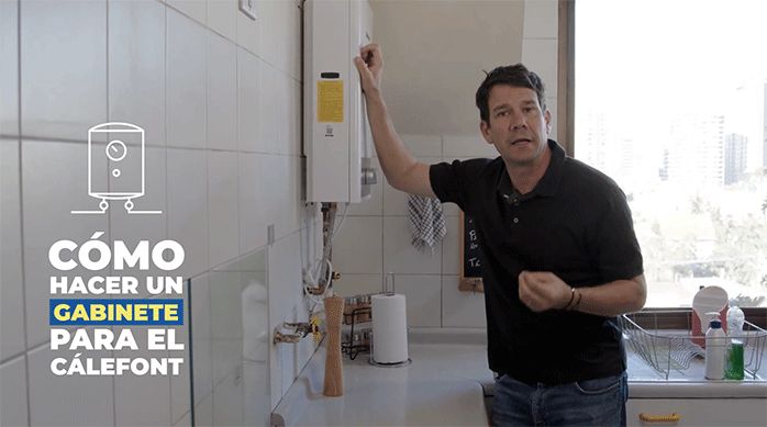un hombre en una cocina al lado de un cálefont.