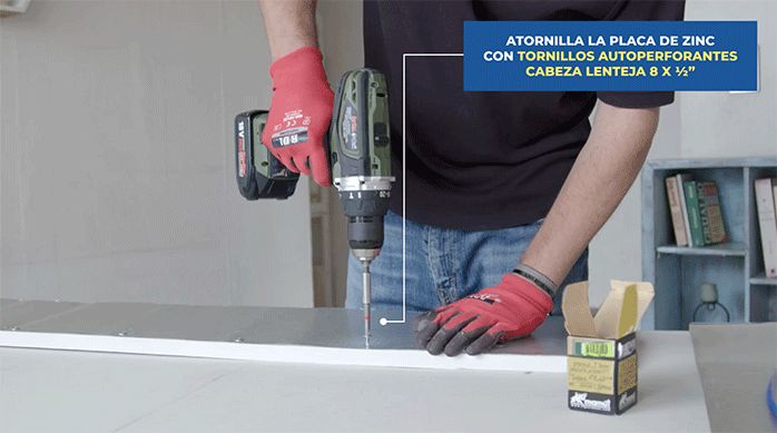 un hombre atornilla una placa de zinc en el trozo de terciado.