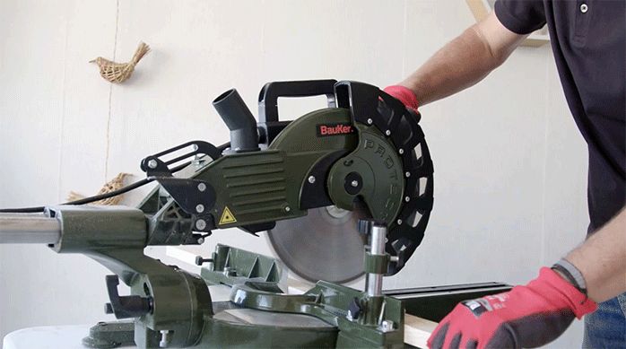 un hombre corta trozos de madera con una sierra ingleteadora.