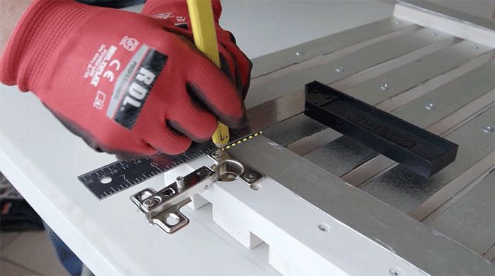 un hombre marca el lugar de la bisagra en un trozo de zinc.