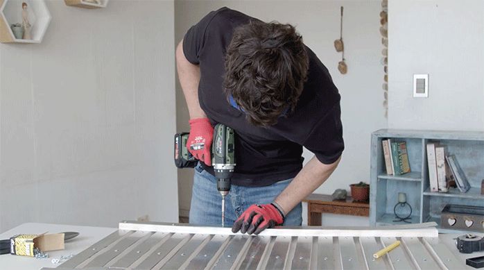 un hombre fija trozos de zinc por el reverso de la puerta del gabinete para calefont.
