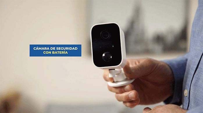 un hombre sostiene una cámara de seguridad con batería marca nexxt.