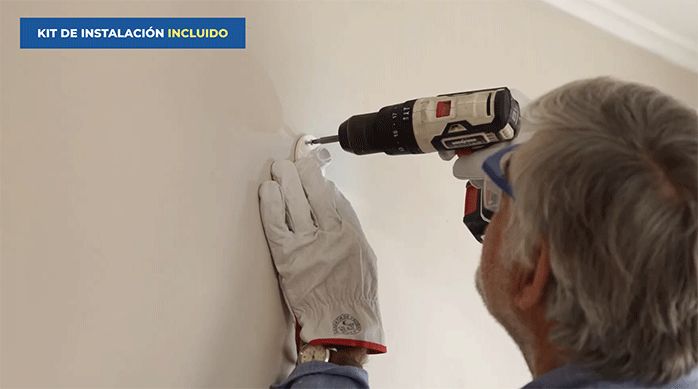 un hombre atornilla el soporte de una cámara de seguridad inteligente en el muro.
