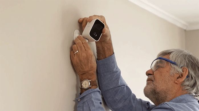 un hombre instala una cámara de seguridad inteligente nexxt en el muro.