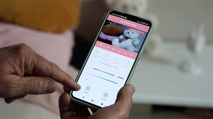 un hombre usa su smartphone para controlar la cámara inteligente de seguridad para pieza de niño.