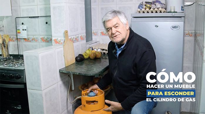 un hombre en una cocina con un cilindro de gas en las manos.