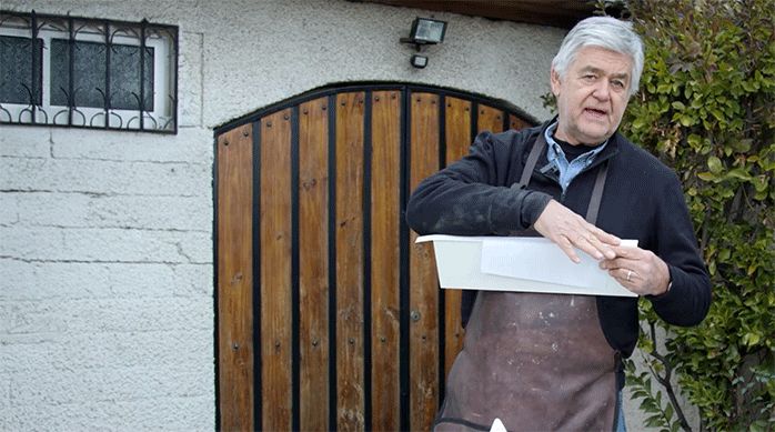 un hombre muestra cómo pegar un tapacanto con una plancha y una hoja de papel.