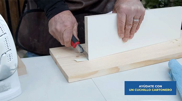 un hombre corta el excedente del tapacanto con un cuchillo cartonero.