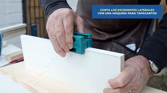un hombre usa una máquina para tapacantos para cortar el excedente de los tapacantos en los cantos de los trozos de melamina.