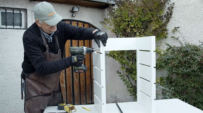 un hombre fija el último trozo de melamina en los laterales del mueble de cocina.