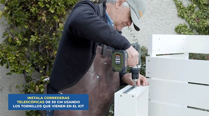 un hombre fija correderas telescópicas o rieles en el cajón del mueble de cocina.