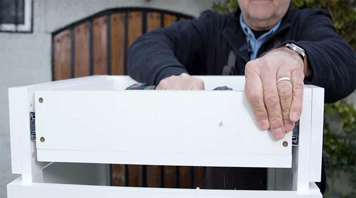 un hombre hace 2 perforaciones en la parte frontal del cajón.
