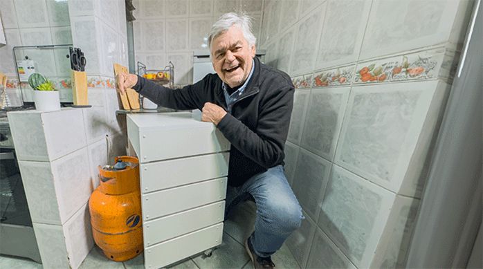 un hombre con un mueble de cocina que está hecho para deslizarse y así ocultar el cilindro de gas.