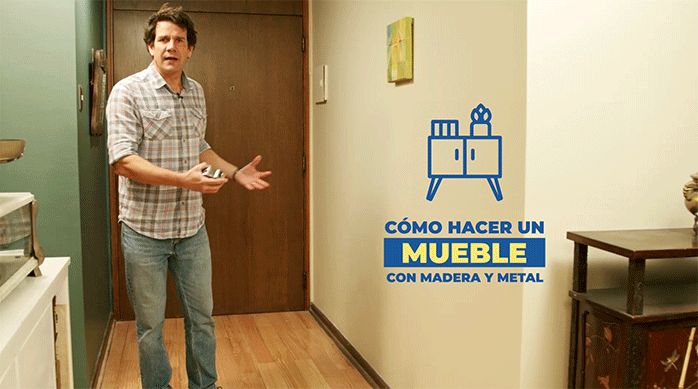 un hombre con camisa cuadrillé y jeans en la entrada de una casa listo para enseñar a cómo hacer un mueble de madera y metal de estilo industrial.