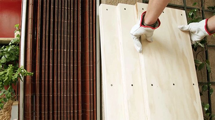 un hombre apoya 3 repisas hechas de terciado en una pared.