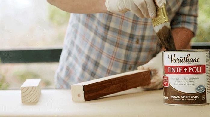 un hombre pinta y protege la madera del mueble con un barniz poliuretano.