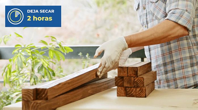 un hombre ordena los trozos de pino seco cepillado que acaba de pintar y proteger con barniz poliuretano.