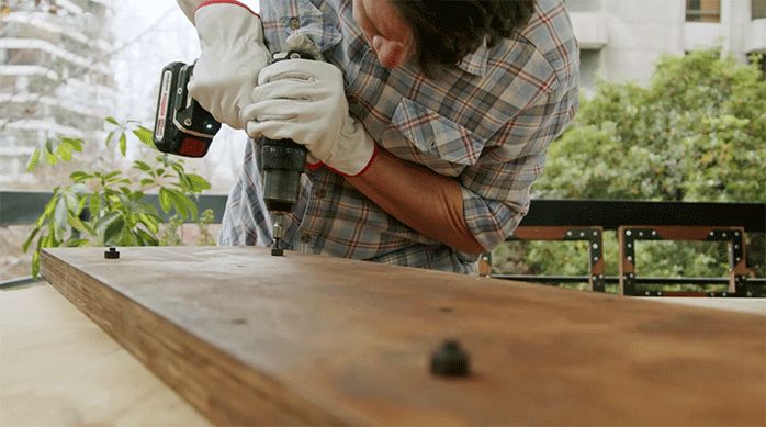 un hombre fija una tuerca en la repisa del mueble de madera y metal.
