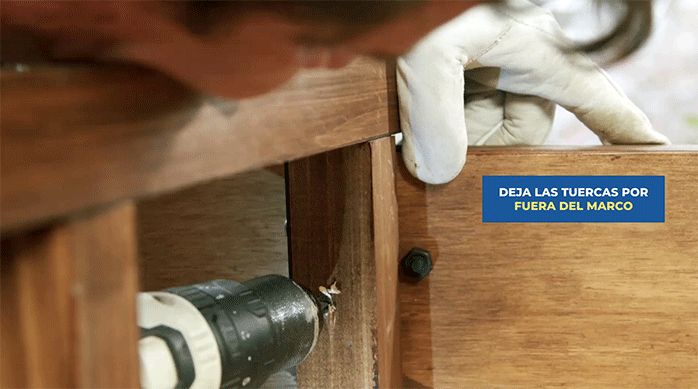 un hombre atornilla la repisa al marco del mueble.