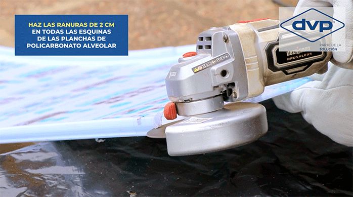 un hombre corta la plancha de policarbonato alveolar con un esmeril angular con disco de corte de 1 mm de espesor.