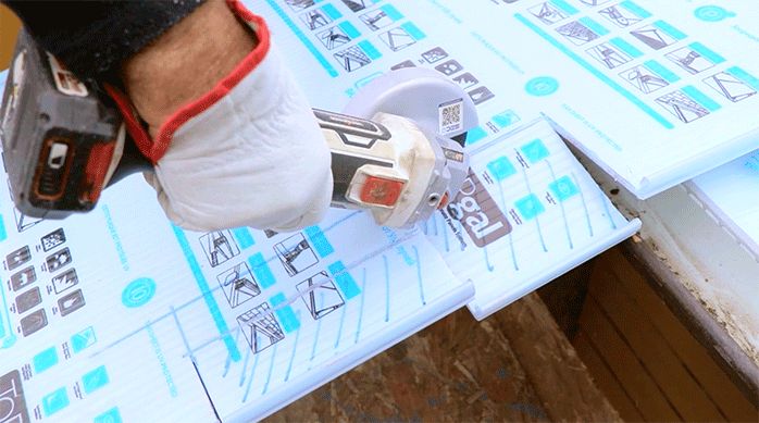 un hombre corta una forma irregular en la plancha de policarbonato con un esmeril angular.