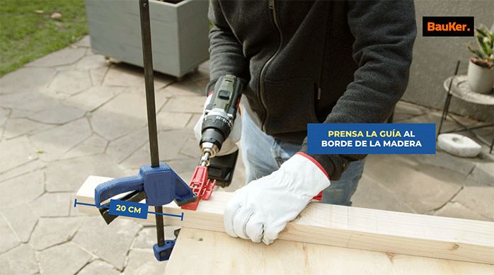 un hombre hace una perforación de bolsillo en un trozo de madera usando una guía especial.