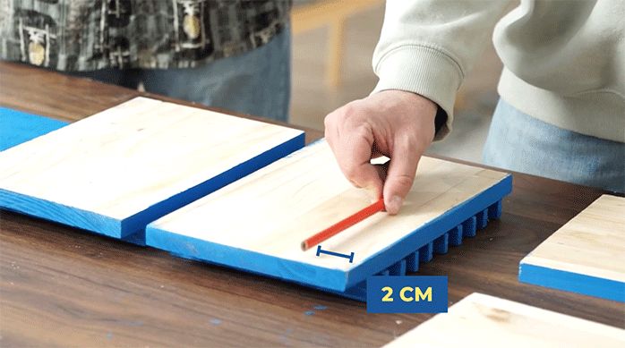 una persona calcula y marca 2 cm desde los lados de los laterales del organizador gamer.