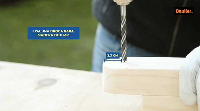 un hombre perfora el extremo de un trozo de madera con una broca para madera de 8 mm.