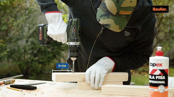 un hombre perfora un trozo de madera.