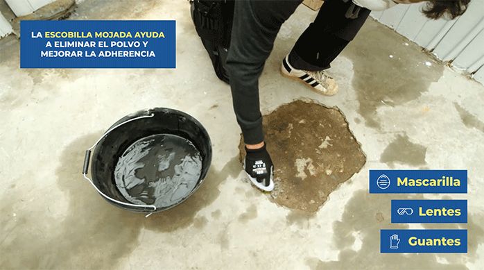 un hombre usa una escobilla de plástico humedecida para limpiar completamente una grieta en un radier.