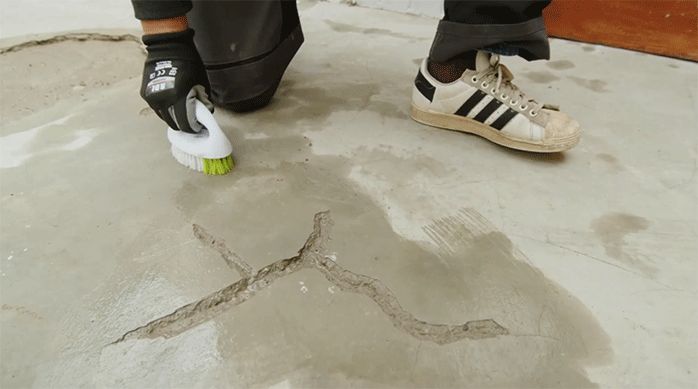 un hombre pasa una escobillado mojada para limpiar completamente la grieta en un radier.