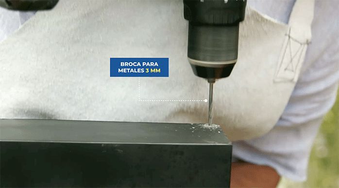 una persona perfora el borde de la parrilla con una broca para metales.