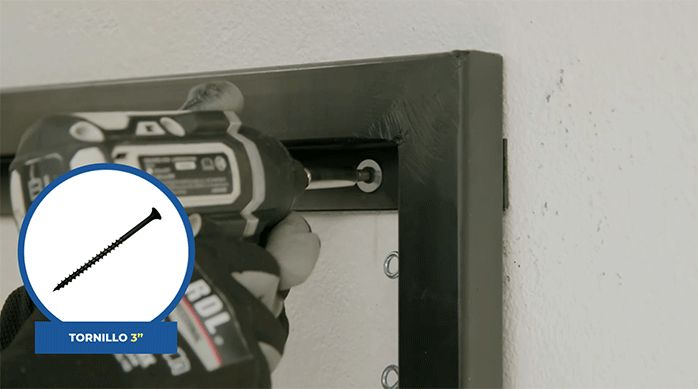 una persona fija la parrilla de pared al muro usando tornillos de 3".