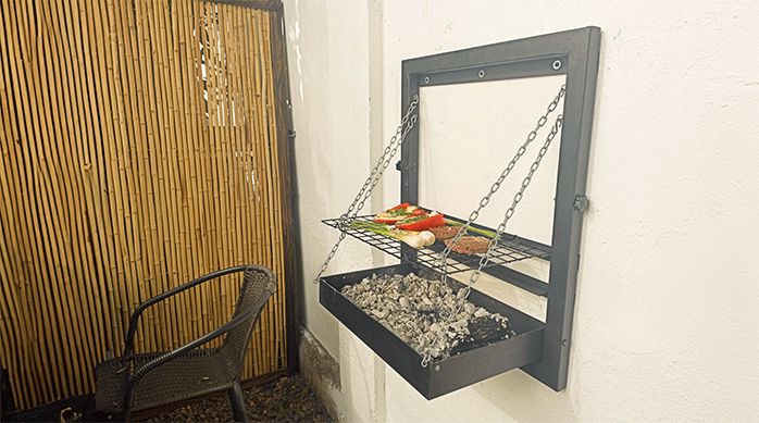 una parrilla de pared en una terraza pequeña, con carbón, carne y verduras.