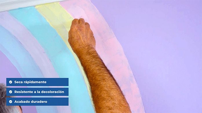 un hombre pinta el mural del rincón de lectura con pintura acrílica de color pastel.