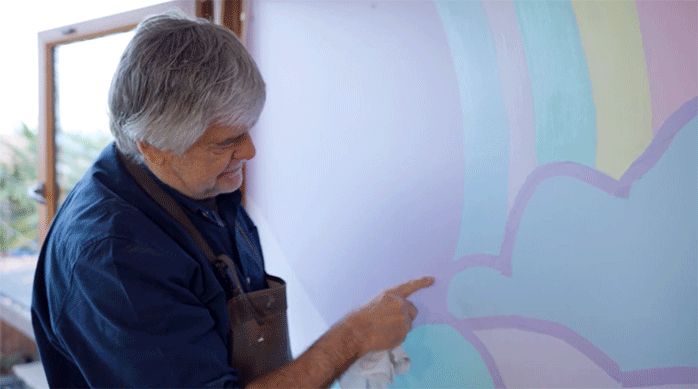 un hombre apunta con el dedo al mural del rincón de lectura para niños.