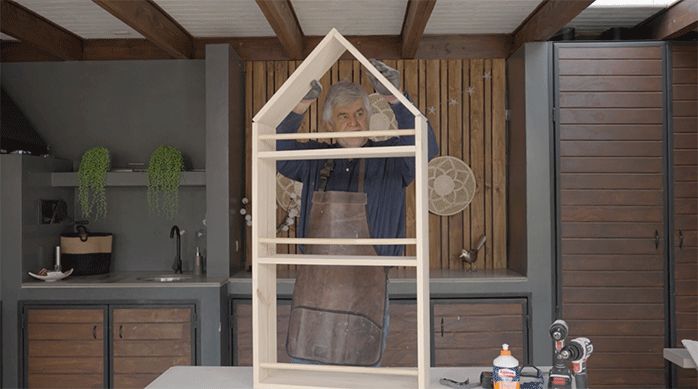 un hombre presenta el techo del librero, que tiene forma de casa.
