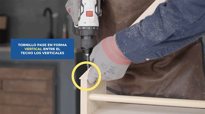 un hombre atornilla el techo del librero.