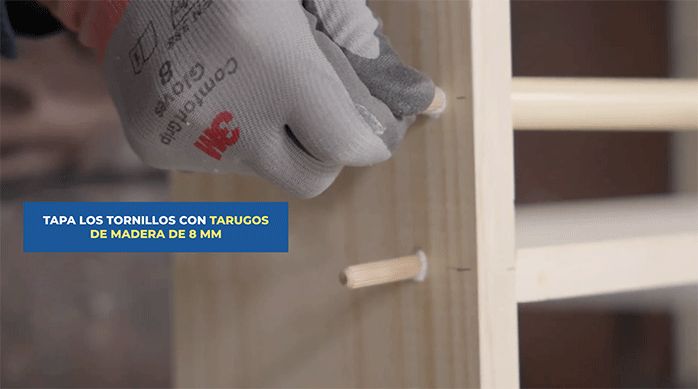 un hombre pone tarugos en los agujeros de las fijaciones.