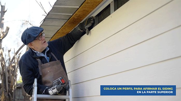 un hombre muestra el perfil de la parte superior de la pared para instalar el siding.