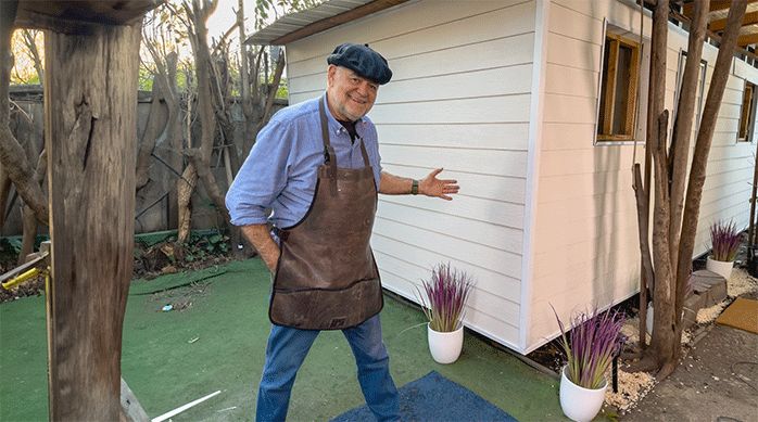 un hombre frente a una casa con revestimiento de siding de fibrocemento.