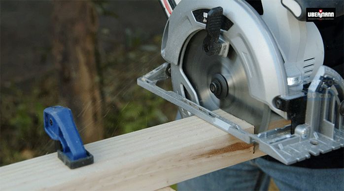una persona usa una sierra circular para cortar un palo de pino seco cepillado.