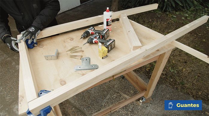 un hombre une un marco de madera que será la estructura base del alero para casa.