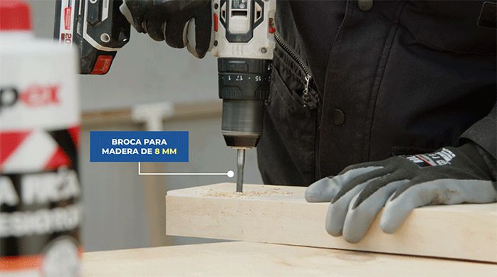 un hombre perfora un lado de un trozo de madera.